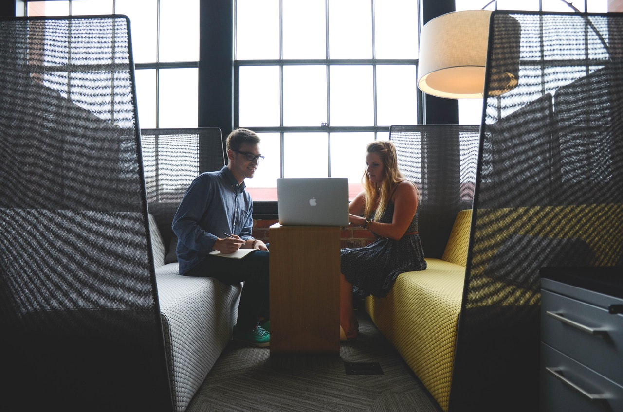 man talking and partnering with a woman professional resume writer in front of a laptop