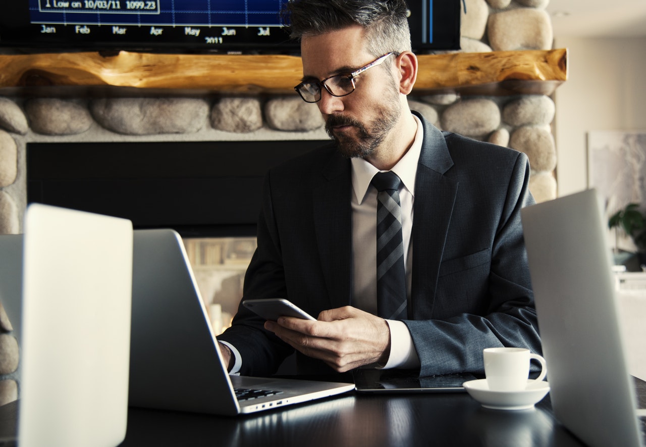 man searching for executive resume writing tips on laptop while holding a mobile phone