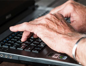 hands of a baby boomer typing and trying to hide her age in resume
