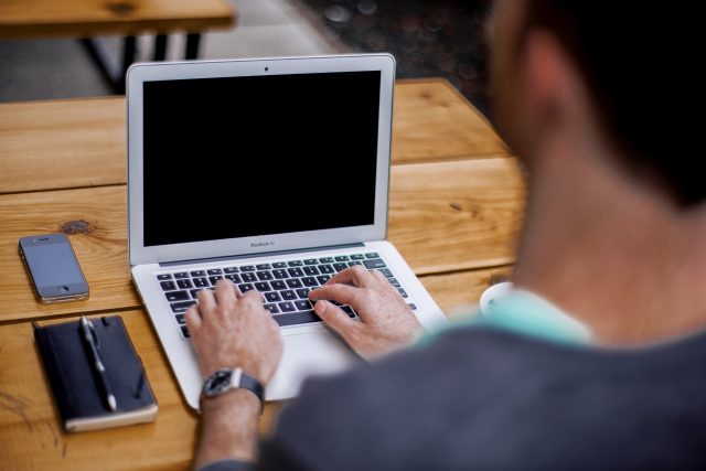 a man typing a mid-level resume in a laptop