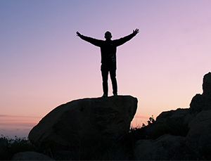 man on hilltop celebrating career success