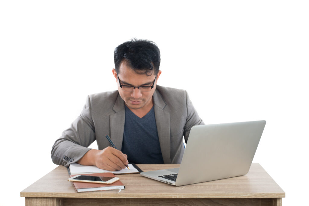 man fixing resume on a writing pad while laptop on table is open