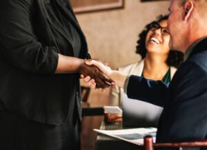 a woman and her boss shaking hands because of the job promotion given to her