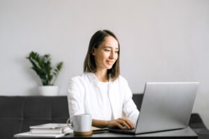 happy young woman sitting at the table and using laptop