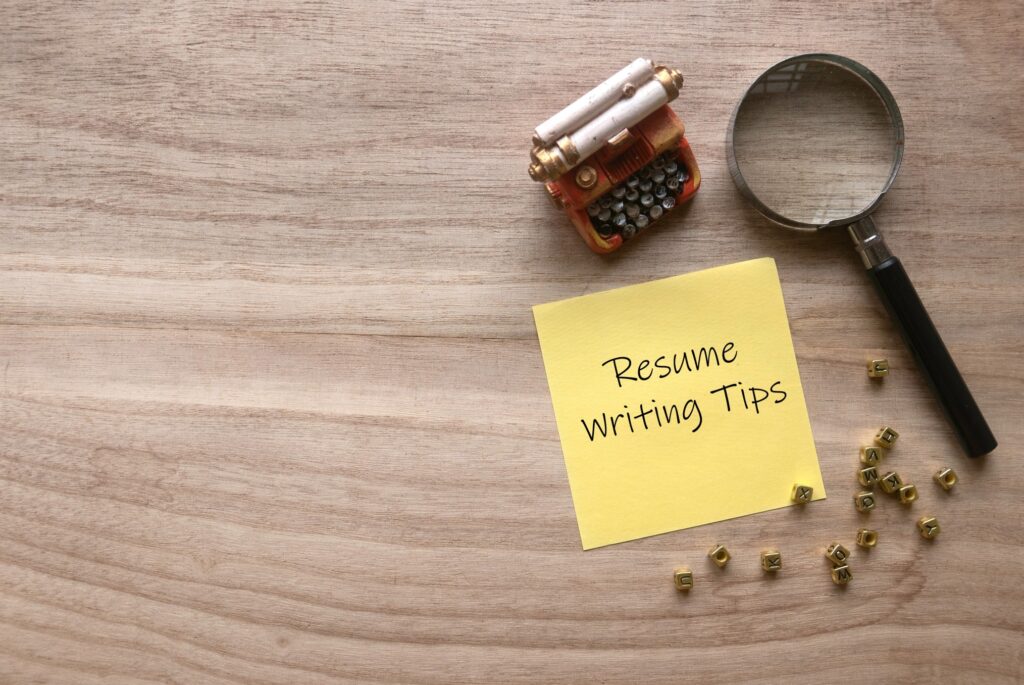 top view of yellow paper note with the words 'resume writing tips'